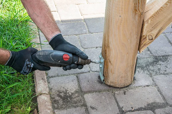 Worker in  gloves use electric screwdriver to tighten the screw.