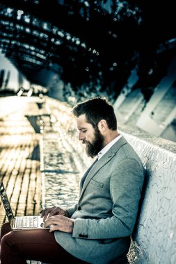 Bussinesman oturmuş elinde tuttuğu dizüstü bilgisayara bakıyor.  