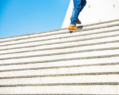 Merdivenlerden çık. İş ayakkabılı adamın alt kısmı merdivenlerden çıkıyor. 