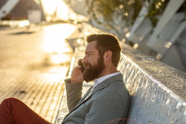 Yönetici elinde bir telefon tutuyor. Genç bir girişimcinin portresi. Şehir merkezinde yeni bir iş merkezi..