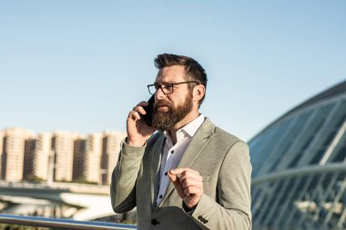 Taşınabilir yaşam tarzı. Yeni teknoloji. Dışarıda cep telefonu olan yakışıklı bir adam. İş iletişimi. Profesyonel kullanım için telefon. 3G mi? 4G mi? 5G mi? Şehir merkezinde telefonu olan bir iş adamı.