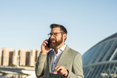 Taşınabilir yaşam tarzı. Yeni teknoloji. Dışarıda cep telefonu olan yakışıklı bir adam. İş iletişimi. Profesyonel kullanım için telefon. 3G mi? 4G mi? 5G mi? Şehir merkezinde telefonu olan bir iş adamı.