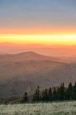 Yüksek irtifada dağların üzerinde renkli bir gün doğumu. Turuncu gökyüzüne karşı siluet dağlarının manzarası.
