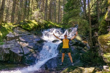 Şelalede yürüyüş yapan genç adam.