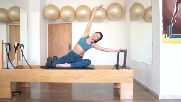 An athletic woman does exercises on a reformer while doing Pilates. 4k — Stock Video