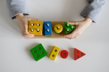 Bir çocuk evde renkli eğitici tahta bir oyuncakla oynuyor. Yakın plan..