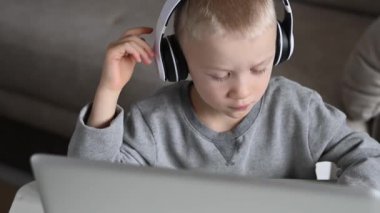 Kulaklıklı beyaz çocuk bilgisayarda video dersi izliyor. 4K