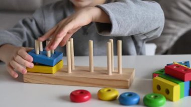 Çocuk renkli, eğitici ahşap bir oyuncakla oynuyor. Yakın çekim 4K