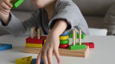 Mutlu bir çocuk renkli bir ahşap oyuncakla oynuyor. Yakın çekim 4K