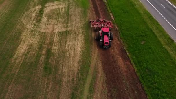 ディスクの矢印を持つトラクターは播種のためのフィールドを耕します。航空写真 — ストック動画