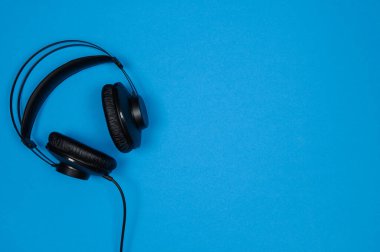 Mavi arka planda siyah kulaklıklar. Üst görünüm. Boşluğu kopyala