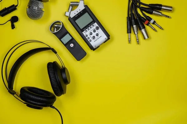 Diseño del ordenador portátil, auriculares, grabadoras, cables en un fondo amarillo.Espacio de copia. — Foto de Stock