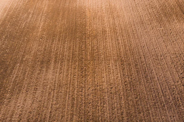 Un campo de color marrón claro arado. Fondo marrón en la vista aérea del campo —  Fotos de Stock