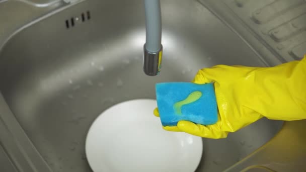 Hands in yellow protective gloves apply detergent and wash the plate — Stock Video