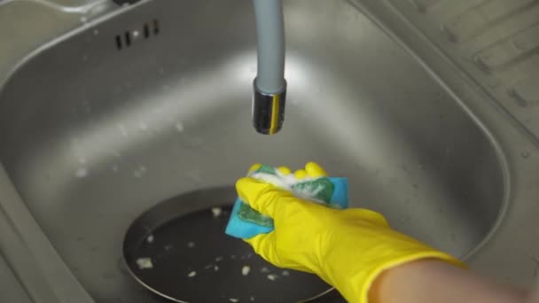 Las manos en guantes protectores amarillos aplican detergente y lavan la sartén — Vídeo de stock
