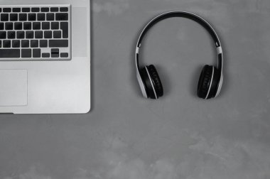 Gri arka planda stereo kulaklıklı bir dizüstü bilgisayar düzeni.