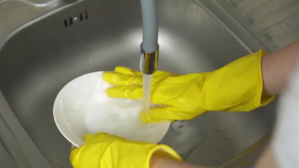 Ręce w żółtych rękawiczkach ochronnych myjących biały talerz — Wideo stockowe