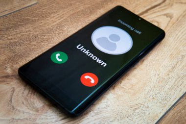Bilinmeyen numaradan aranmış. Dolandırıcılık, dolandırıcılık ya da akıllı telefon konseptiyle dalavere. Telefon şakacısı, dolandırıcı ya da yabancı. Bilinmeyen bir telefondan, ahşap bir masadaki bir akıllı telefondan..