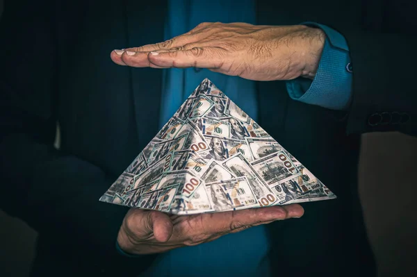 詐欺師の手によるピラミッド型の計画です 金融市場における取引所の概念は 資本主義の金融システムの崩壊です — ストック写真