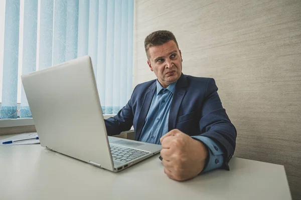 Angry man hits table with his fist. Concept of anger. angry businessman in a jacket slams his fist on table in anger looks away. boss is dissatisfied with the work of employees. fury