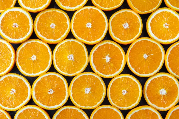 Healthy food, background. Orange. Sliced orange slices on a dark table. Lots of citrus fruits cut in half to make juice
