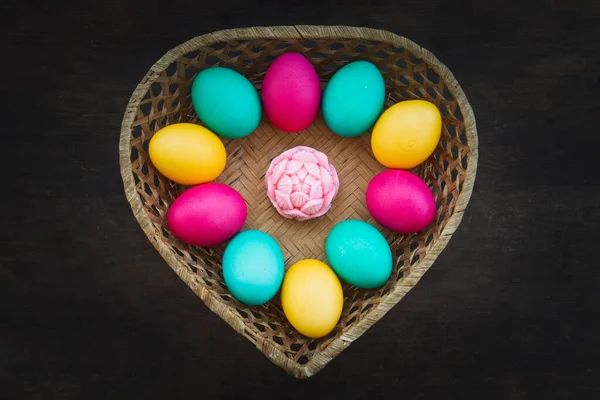 Easter eggs in weaved basket on black background. a basket made of straw in the form of a heart with colorful eggs painted for the holy orthodox Christian Easter holiday.