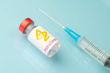Mavi zemin üzerinde açık bir sıvı bulunan cam ampul bir ilaç şirketi astrazeneca logosu. 15 Mart 2021. Barnaul, Rusya.