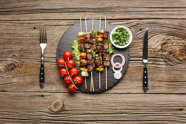 Délicieuse brochette de viande ardoise noire avec fourchette couteau à beurre table en bois. Haute qualité beau concept photo — Photo