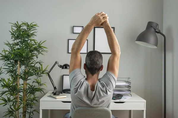 Vista trasera hombre escritorio estiramiento mientras se trabaja desde casa. concepto de foto hermosa de alta calidad —  Fotos de Stock