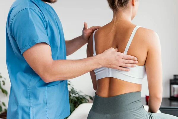 侧视男性骨病理学家检查女性病人肩胛骨。高质量的照片 — 图库照片