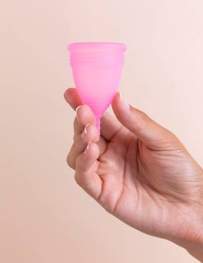 Pembe aybaşı bardağını tutarken elinizi kapayın. Yüksek kalite fotoğraf