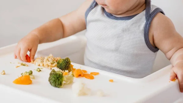 Schattige baby jongen kinderstoel kiezen wat eten. Hoge kwaliteit foto — Stockfoto