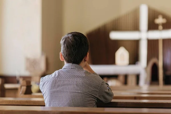 Vue arrière jeune garçon priant église. Photo de haute qualité — Photo