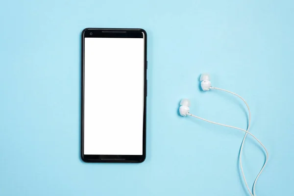 Biały pusty ekran wyświetlacz telefonu komórkowego ze słuchawkami na niebieskim tle. Wysokiej jakości zdjęcie — Zdjęcie stockowe