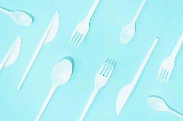 white disposable cutlery composition turquoise background. High quality photo