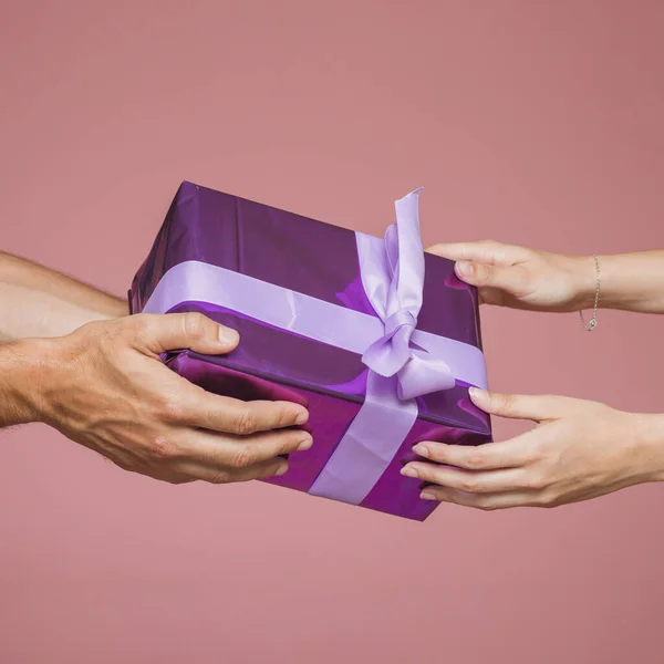 Two hands holding purple gift boxes against colored background. High quality photo — Stock Photo, Image