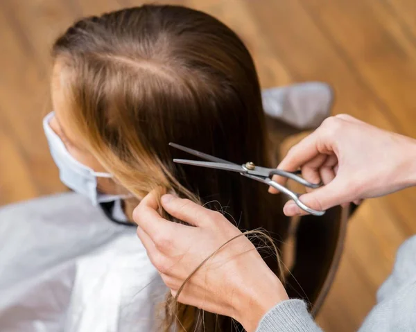 Menina de ângulo alto recebendo corte de cabelo enquanto usava máscara médica. Foto de alta qualidade — Fotografia de Stock