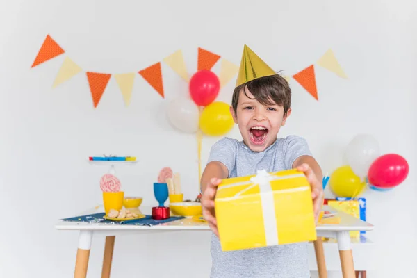 Niño alegre tomando caja de regalo amarilla con cinta blanca. Foto de alta calidad — Foto de Stock