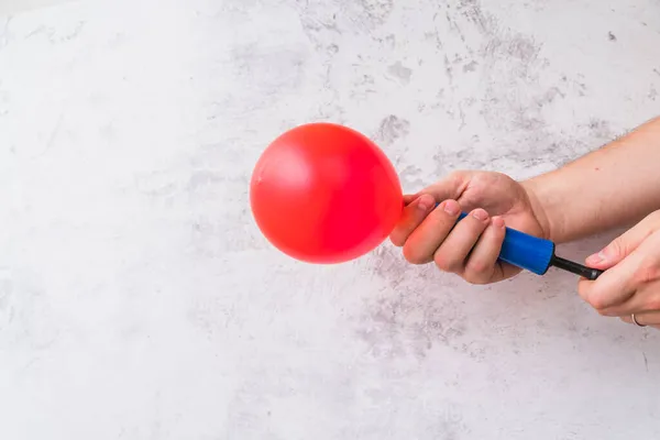 Duvara karşı pompayla kırmızı balonu şişirin. Yüksek kalite fotoğraf — Stok fotoğraf