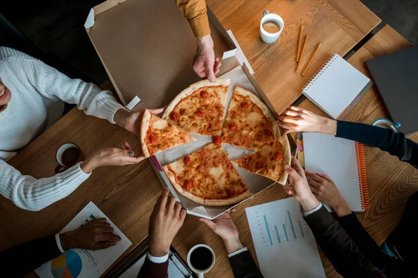 stock image top view colleagues having pizza during office meeting break. High resolution photo