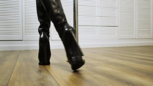 Detailní záběr tanečníkových nohou u sloupu. Nohy v černých vysokých podpatcích, pohyb v taneční pohyb na podlaze.