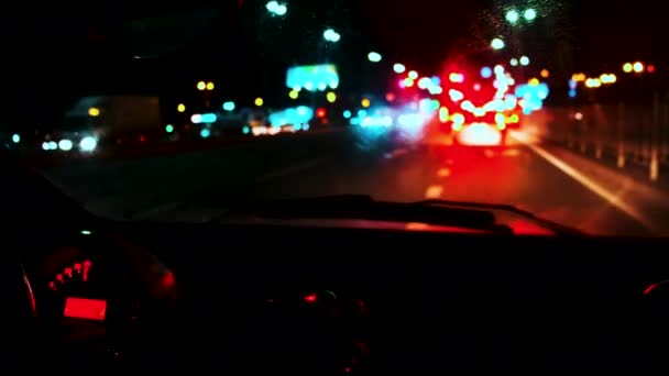 Widok z przedniej szyby samochodu. Porusza się nocą wzdłuż autostrady, skręca w prawo za innymi samochodami. — Wideo stockowe
