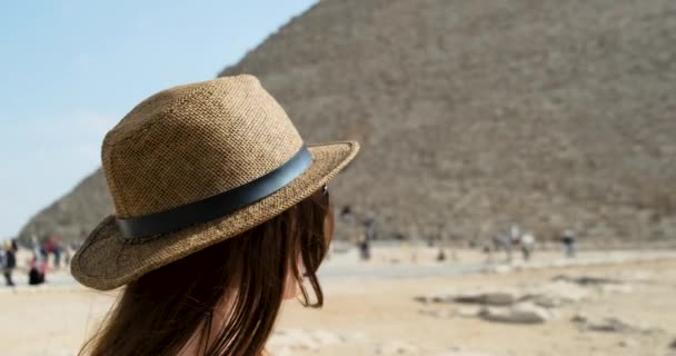 Meisje met strohoed kijkt naar de Egyptische piramide van Gizeh in Caïro. Heldere dag, blauwe lucht, slow motion, wijd beeld — Stockvideo