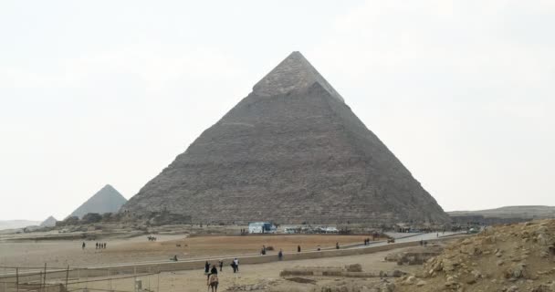 Uitzicht op de piramide van Gizeh in Egypte. Een menigte toeristen, voor de piramide. Heldere dag, wijd schot, blauwe lucht — Stockvideo