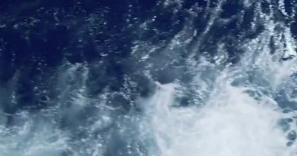 Vista dall'alto delle onde blu che la nave taglia. Schiuma bianca e un po 'tempestosa, primo piano. Le onde si stanno allontanando dalla nave. — Video Stock