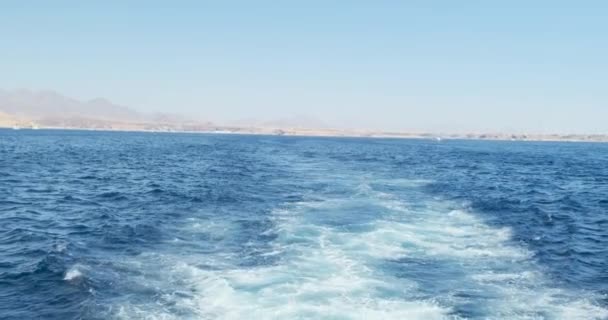 Vue des vagues divergentes du navire. Horizon avec côte. Jour clair, mousse après la vis, le désert d'Egypte en arrière-plan. Plan large, ralenti — Video
