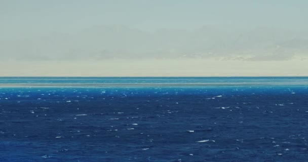 The dark blue and blue sea is a little stormy, at the backdrop of a deserted coast in Sharm El Sheikh, Egypt. Широкий выстрел, ясный день, замедленная съемка — стоковое видео