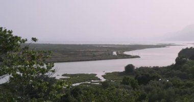Arnavutluk, Butrint, ulusal park, nehir denize dökülüyor. Gün batımında yeşil çayır, arka planda orman ve dağlar. geniş çekim