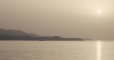 Denizde gün batımı zamanı, denizin üstünde turuncu güneş, dağlar ve deniz yüzeyi. Ksamil, Arnavutluk