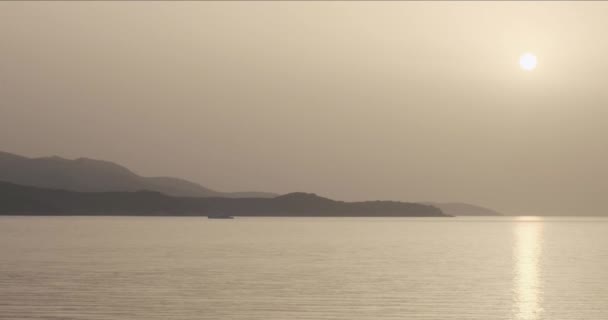 Napnyugtakor a tengeren, narancssárga nap magasan a tenger felett, hegyek és a tenger felszínén. Ksamil, Albánia — Stock videók